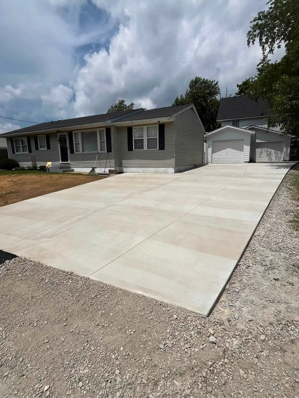 Wide new concrete driveway poured in front of a ranch home
